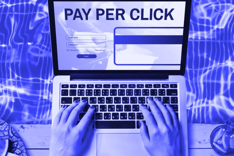 Hands typing on a laptop showing a pay-per-click screen